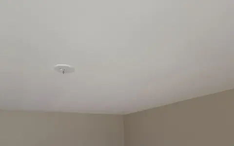 Ett vitt tak med en krok för en lampa. Väggarna är ljusbruna. Snart dags att måla taket för en fräschare känsla.