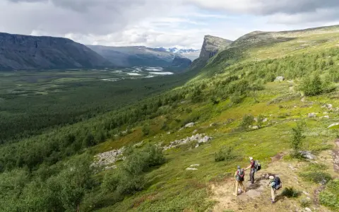 Vandrare njuter av utsikten över Sarek nationalpark, med en vidsträckt dalgång och slingrande floder.