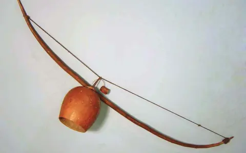 Drewniany łuk muzyczny instrument z tykwą jako pudłem rezonansowym.
