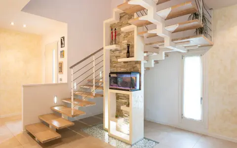 Moderna scala interna in legno e metallo, con acquario integrato e decorazioni in pietra. Un esempio di design che valorizza il costo scala interna.