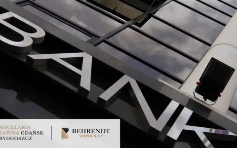 Litery "BANK" na fasadzie budynku, odbijające się w szklanej elewacji.