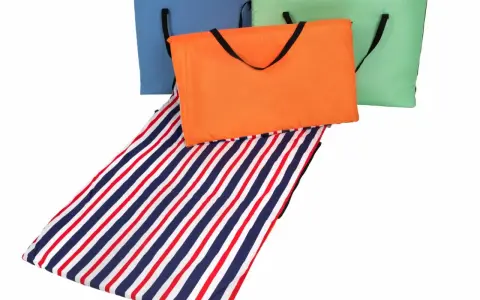 Składane maty plażowe w kolorach: niebieskim, pomarańczowym i zielonym, z jedną rozłożoną, w paski. Idealne na plażę kamienistą.