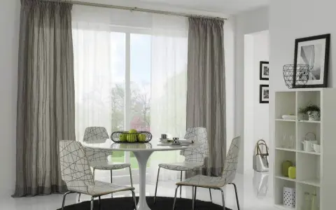 Ein Essbereich mit einem runden Tisch, vier Stühlen und einem Fenster, das von einer Gardinenschiene oder Stange mit grauen und weißen Vorhängen eingerahmt wird.