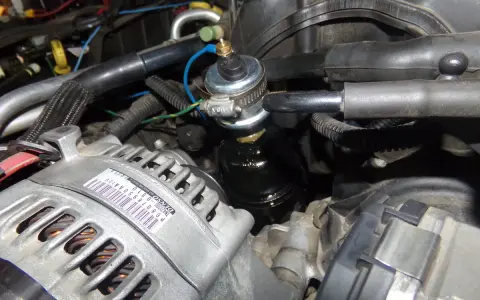Close-up of a p0520 Dodge engine bay, showing the alternator and a fuel pressure regulator.
