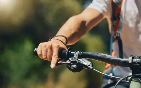 Dłoń rowerzysty zaciska się na kierownicy, czując narastające drętwienie rąk na rowerze.