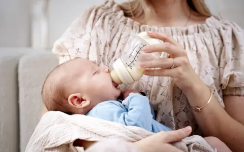 Mama karmi maluszka z butelki, która może być najlepszą butelką antykolkową dla noworodka.