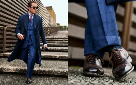 Un giovane uomo con un completo blu a quadri, cappotto scuro e occhiali da sole, cammina con passo sicuro. Un vero old money boy.