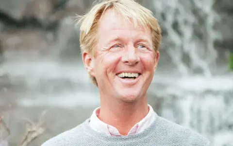 Glad man med blont hår och ljus tröja, skrattar hjärtligt. En natthiko Lindeblad i sin bästa stund.