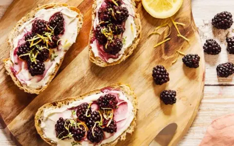 Tartines de pain grillé avec fromage frais, mûres et zeste de citron. Un encas healthy et gourmand, parfait pour un petit-déjeuner ou une pause.