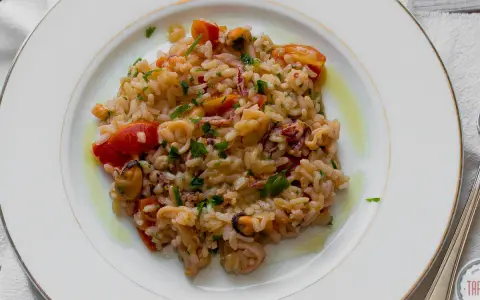 Pyszne risotto z owocami morza, z pomidorkami i natką pietruszki, polane oliwą.