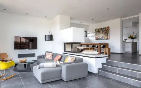 Modernes Split-Level-Haus mit offenem Wohnbereich, Kamin, Essbereich und Küche. Ein Kater döst auf dem Sofa.