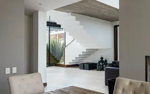 Moderna escalera blanca con un diseño flotante. El **rellano escalera decoracion descansillo escalera** se realza con linternas negras y maceteros.