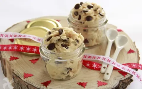 Två glasburkar fyllda med chokladbitsdeg, perfekt för ett enkelt cookie dough recept. Dekorerat med julband och små granar.
