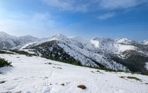 Śnieżny szlak na Grzesia w Tatrach. W oddali widać ośnieżone szczyty i lasy.