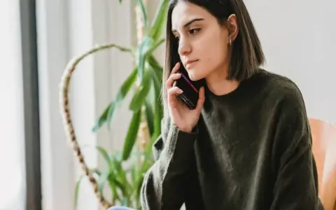 Zmartwiona kobieta rozmawia przez telefon, zastanawiając się, czy pracodawca może cofnąć urlop.