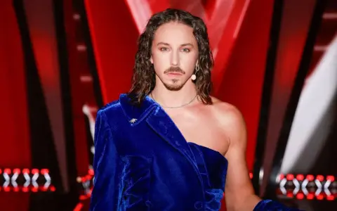 Mężczyzna w niebieskiej, aksamitnej marynarce, z długimi włosami i wąsami, wygląda jakby przygotowywał się do występu na Eurowizji.