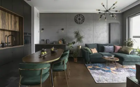 Nowoczesny czarny salon z drewnem, zielona kanapa, owalny stół i designerska lampa.