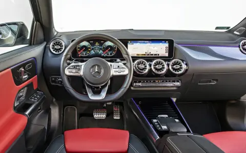 Wnętrze Mercedesa GLA 200 z czerwono-czarną tapicerką, nowoczesnym kokpitem i ekranem nawigacji.