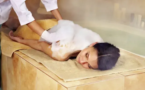 Eine Frau genießt eine Schaummassage im Hamam. Die Bedeutung von Hamam liegt in der tiefen Entspannung und Reinigung.