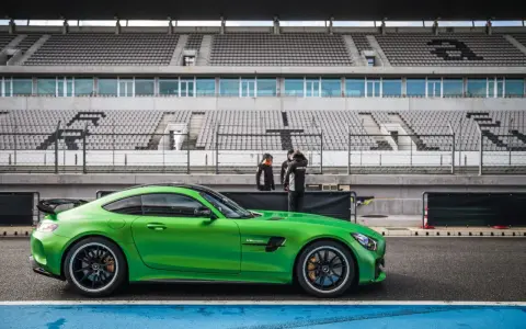 Zielony Mercedes GTR na torze wyścigowym, gotowy do jazdy. Za nim puste trybuny stadionu.