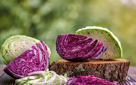 Cavolo cappuccio rosso e bianco tagliati a metà, con foglie sminuzzate.