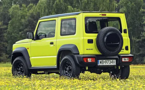 Jaskrawożółty Suzuki Jimny na tle łąki z żółtymi kwiatami. Sprawdź aktualną suzuki jimny cena i wybierz się na przygodę!