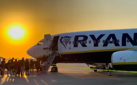 Ryanair loty za 1 zł – pasażerowie wsiadają do samolotu o zachodzie słońca.