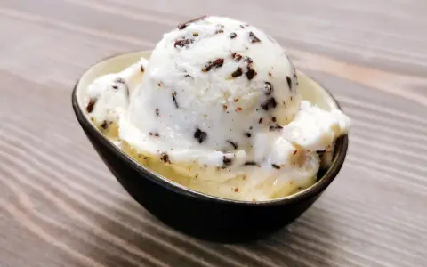 Ein Löffel cremiges Stracciatella-Eis mit zarten Schokoladenstückchen in einer Schale.