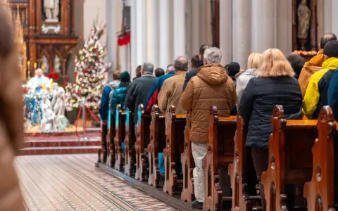 Ludzie siedzą w kościele przy choince. Czy w drugi dzień świąt trzeba iść do kościoła?
