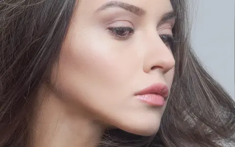 Delikatny makijaż glow podkreślający naturalne piękno. Skóra promienieje subtelnym blaskiem, a usta są muśnięte różowym błyszczykiem.