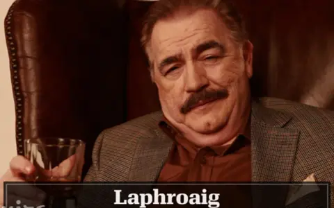 Mann mit Schnurrbart hält Glas Whisky. Die Laphroaig Aussprache ist wichtig für Kenner.