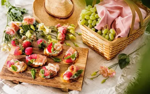 En härlig picknick med jordgubbsbruschetta, vindruvor i korg och blommor på en **picnic mat**.