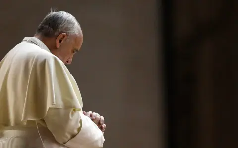 Papież Franciszek w białej szacie, z rękami złożonymi do modlitwy do Ojca Świętego.