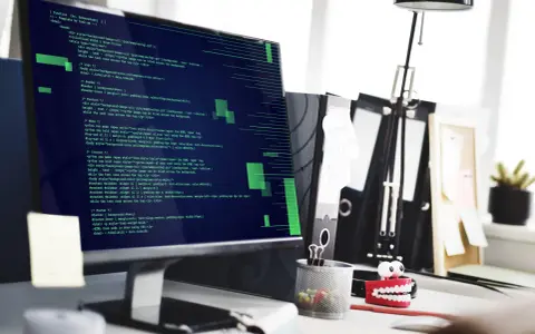 Tester oprogramowania analizuje kod na ekranie komputera.