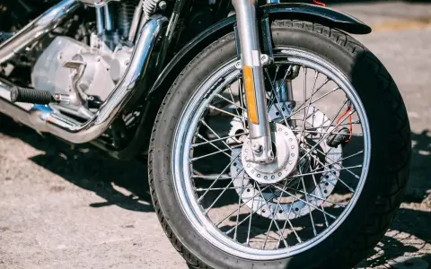 Zbliżenie na koło motocykla z widocznym silnikiem i chromowanymi elementami.