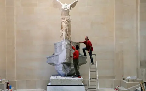 Deux personnes travaillent sur la Victoire de Samothrace, dont la signification symbolise la victoire et la liberté.