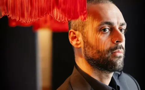 Ardalan Esmaili, med ansiktet belyst av ett randigt ljus, tittar bort.
