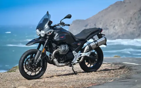 Moto Guzzi V85TT nera, pronta per esplorare, con la sua velocità massima che promette avventure sul mare.