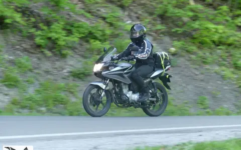 Motocyklista pokonuje zakręt na przełęczy Przysłup, otoczony zielenią górskich zboczy.
