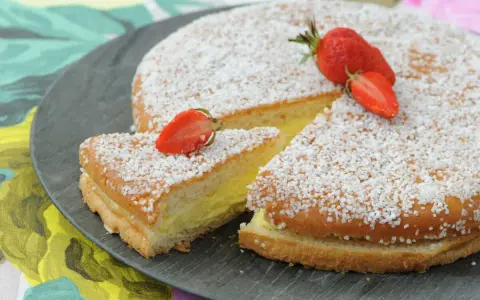 Un délicieux gâteau génoise crème pâtissière, saupoudré de sucre et garni de fraises fraîches.
