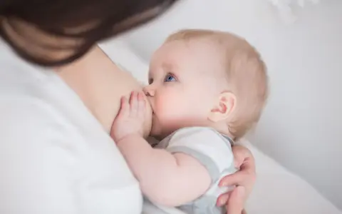 Niebieskooki niemowlak karmiony piersią. Czasem pojawia się kryzys laktacyjny, ale to naturalny etap.