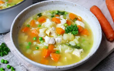 Herzhafte Hühnersuppe mit Reis, Karotten und Erbsen. Ein ideales Gericht für kalte Tage, das zu den besten Suppen Rezepten zählt.
