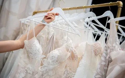 Une main choisit une robe de mariée, révélant la beauté des dentelles et des broderies. Quel tissu pour robe de mariée ? Ici, la délicatesse est reine.