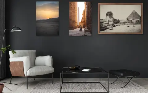 Trois tableaux sur un mur sombre : un coucher de soleil sur les dunes, une personne marchant dans un temple égyptien, et le Sphinx et les pyramides. La **couleur référence** de la pièce est le gris anthracite.