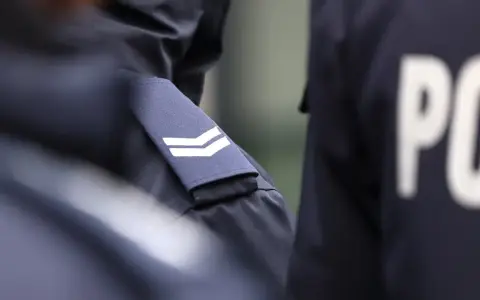 Zbliżenie na mundur policyjny z naszywkami i literami "PO".