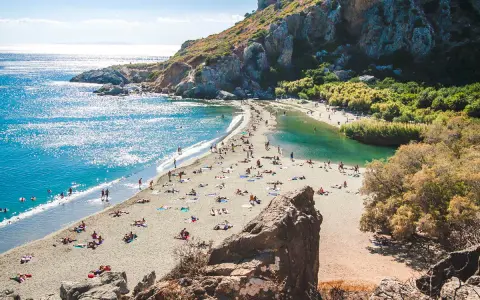 Słoneczny dzień na plaży Preveli. Ludzie odpoczywają na piasku, kąpiel w turkusowej wodzie laguny i morza.