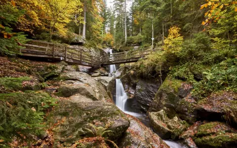 Herbstliche Szenerie mit Wasserfall und Holzbrücken im Bayerischen Wald. Perfekt für Ausflugsziele.