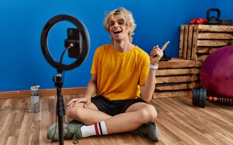 Joven influencer de fitness sonríe y señala, listo para grabar sus acciones con influencers.