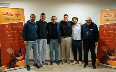 Roberto Carballes Baena posa con otros hombres frente a un cartel del Open Menorca ATP Challenger 100.