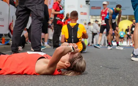 Zmęczona biegaczka leży na ziemi po tym, jak dowiedziała się, ile biegnie się maraton.